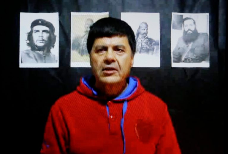 In this Monday, Jan. 20, 2014 screen image, member of the Greek November 17 terrorist group Christodoulos Xiros makes an Internet statement posted Monday and purportedly written by him on Jan. 14 which rails against the Greek financial crisis. Xiros, a  fugitive who vanished on furlough from prison while serving six life sentences for left-wing bombings and shootings has vowed a return to armed action, in a video posted Monday, Jan. 20, 2014 on the Internet. Seen in the background from left to right are portraits of Argentine Revolutionary Che Guevara, Greek Independence War heroes Georgios Karaiskakis and Theodoros Kolokotronis, and World War II Greece guerrilla resistance leader Aris Velouchiotis. (AP Photo/Thanassis Stavrakis)