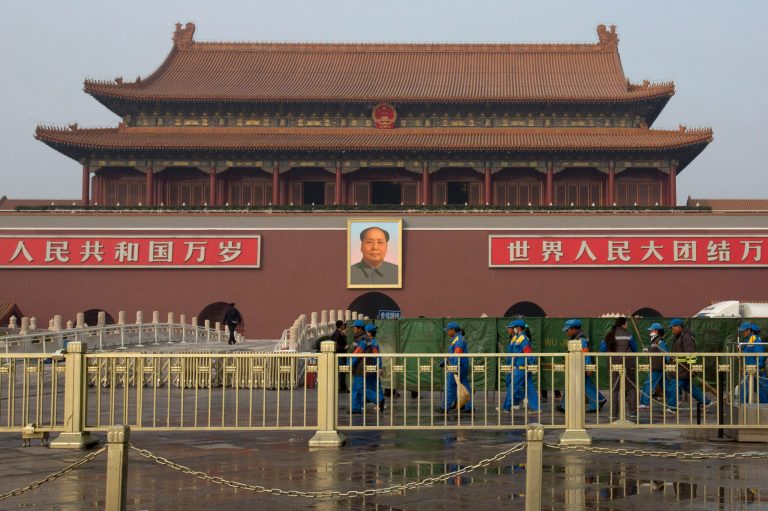 FILE - In this Oct. 28, 2013 file photo, cleaners walk past an area shielded by green nets in front of Tiananmen Gate after a car plowed through tourists and ended up in a fiery crash at the gate in the heart of Beijing, killing two bystanders and the three attackers. A court in western China sentenced three people to death Monday, June 16, 2014 for planning the deadly car ramming at Beijing's iconic Tiananmen Gate last year that was blamed on Muslim separatists, state media reported. (AP Photo/Alexander F. Yuan, File)