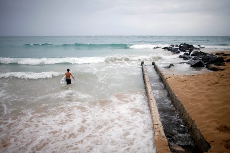 A surfer enters the water to take advantage of the high waves in San Juan, Puerto Rico, Saturday, Aug. 2, 2014. Bertha pushed just south of Puerto Rico on Saturday as it unleashed heavy rains and strong winds across the region.(AP Photo/Ricardo Arduengo)
