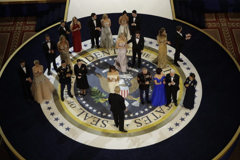 President Donald Trump turns to look at others on stage at The Salute To Our Armed Services Inaugural Ball in Washington, Friday, Jan. 20, 2017. (AP Photo/Evan Vucci)