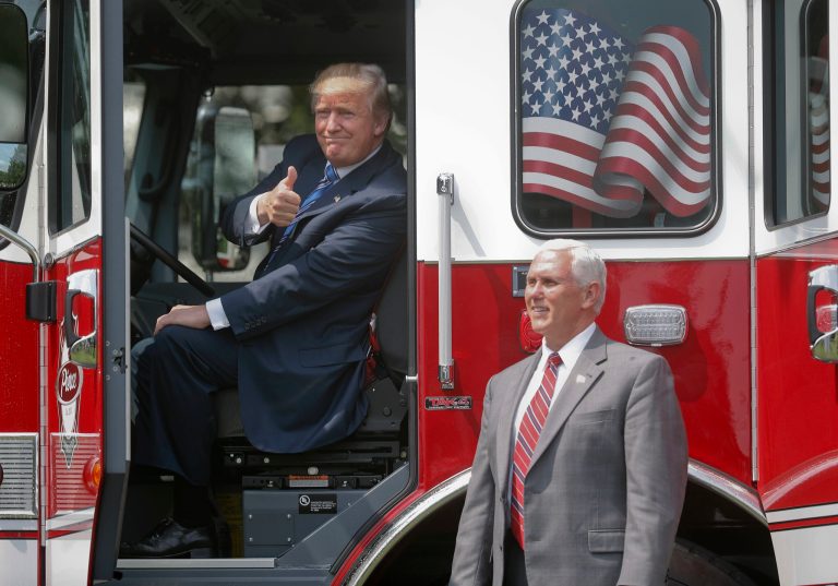 President Donald Trump, accompanied by Vice President Mike Pence, gives a 'thumbs-up' from inside the cabin of a firetruck during a 