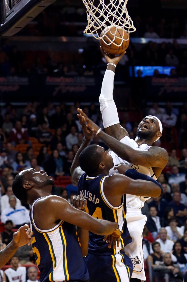  Miami Heat's LeBron James, right, shoots over Utah Jazz's Paul Millsap and Al Jefferson, left, during the first half of an NBA basketball game in Miami, Saturday, Dec. 22, 2012. (AP Photo/Alan Diaz)  