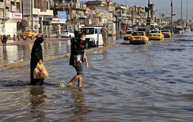   An Iraqi family make their way through flood water, after heavy rain fell in Baghdad, Iraq, Wednesday, Dec. 26, 2012. (AP Photo/Karim Kadim)  