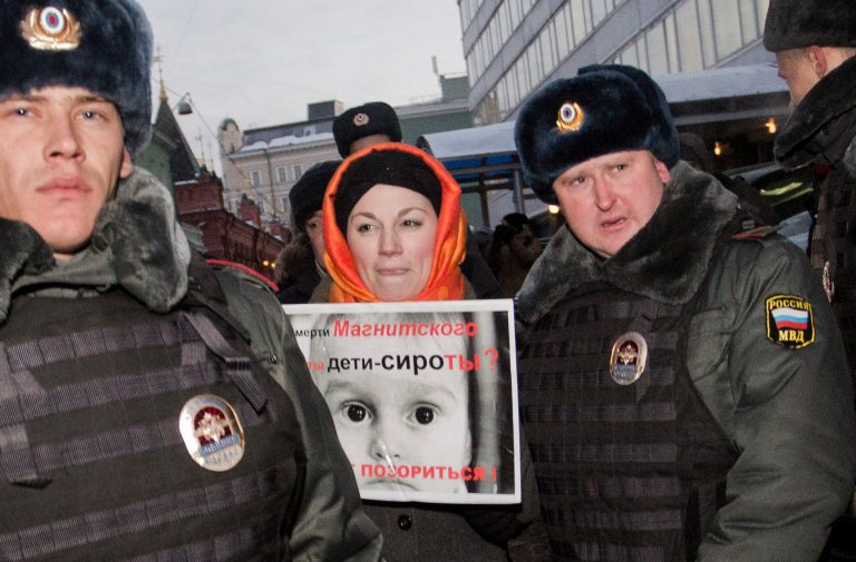   Police officers detain a protester near the State Duma, in Moscow, Russia, Wednesday, Dec. 19, 2012. People picket parliament's lower chamber, to protest against planned debate of an amendment that would ban Americans from adopting Russian children. The poster reads: Are orphans guilty of Magnitsky's death ? Stop putting shame on yourselves! Sergei Magnitsky, a Russian lawyer who was arrested by the officials he accused of a $230 million tax fraud. He was repeatedly denied medical treatment and in 2009 died in jail. (AP Photo/Novaya Gazeta, Yevgeny Feldman)  