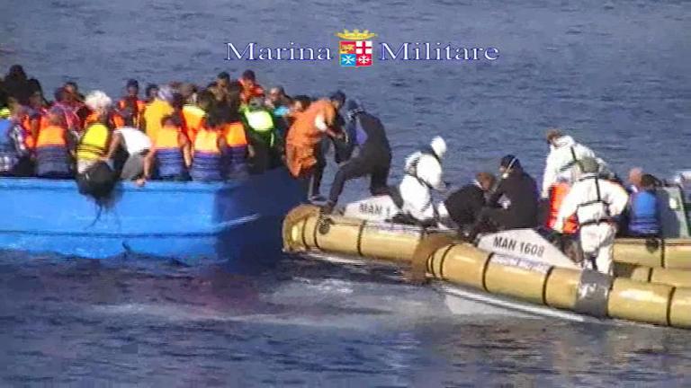 This image taken from video provided by the Italian Navy (Marina Militare) Saturday, Aug. 15, 2015, shows an Italian Navy RIB rescuing migrants from a fishing boat, off the coast of Libya. At least 40 migrants died on Saturday in the hold of an overcrowded smuggling boat in the Mediterranean Sea north of Libya, apparently killed by fuel fumes. (Marina Militare via AP)