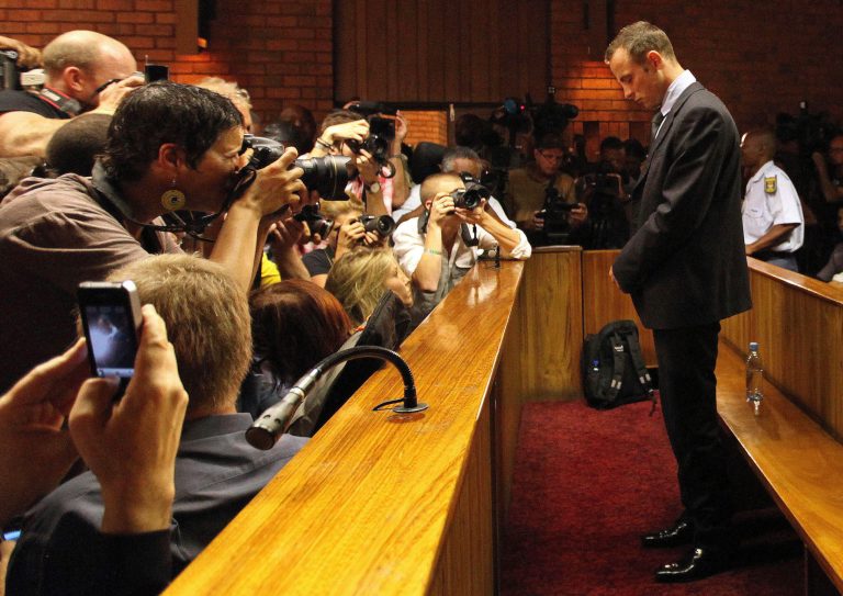 File - In this Wednesday, Feb. 20, 2013 file photo Olympic athlete Oscar Pistorius stands inside a court during his bail hearing at the magistrate court in Pretoria, South Africa. Pistorius will defend himself March 3, 2014 against a charge of premeditated murder in the slaying of his girlfriend Reeva Steenkamp. A South Africa judge has ruled that television stations can broadcast parts of the trial live, but with restrictions on witness testimonies.  (AP Photo/Themba Hadebe, File)