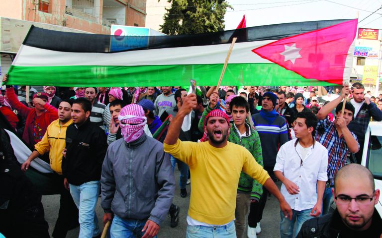 Jordanian loyalists, some armed with wooden sticks and batons to threat their critics, march in the streets while chanting pro-King Abdullah slogans and carrying a Jordanian flag in Irbid, Jordan, Friday, Nov. 16, 2012. Despite the appearance of counter protesters, Jordanian authorities reported no clashes in the 10 demonstrations that took place across the country on Friday. (AP Photo/Mohammad Hannon)