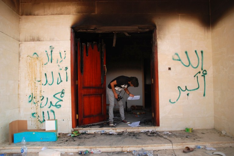 FILE - In this file photo taken Wednesday, Sept. 12, 2012, a man looks at documents at the U.S. Consulate in Benghazi, Libya, the day after an attack that killed four Americans, including Ambassador Chris Stevens. A strange silence has met the U.S. capture of a Libyan militant accused in the 2012 attack that killed the American ambassador and three others. In his hometown of Benghazi in eastern Libya, there have been few threats of revenge, only speculation among supporters and opponents that Ahmed Abu Khattala was betrayed by an insider. (AP Photo/Ibrahim Alaguri, File)