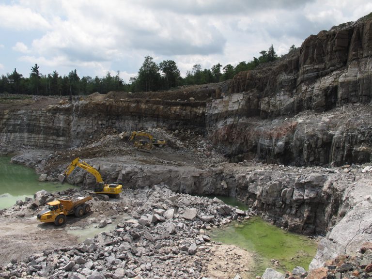 FILE - This July 9, 2013 file photo shows miners using heavy equipment to dig wollastonite ore from a pit mine in the Adirondacks. Mining company NYCO Minerals, must delay test drilling on Adirondack Forest Preserve land under a temporary restraining order issued Wednesday, July 16, 2014 from a state judge after environmental groups filed a lawsuit. (AP Photo/Mary Esch, File)