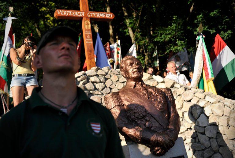   This photo taken June 16, 2012 shows a member of the controversial far-right Hungarian Guard standing by the unveiled bust of Admiral Miklos Horthy, Hungary's WWII ruler in Csokako, Hungary. Erecting a memorial for the controversial Horthy was welcomed by the Hungarian right wing, while the act was widely criticized by the country's liberal society. (AP Photo/Bela Szandelszky)  