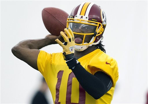 FILE - This May 21, 2012 file photo shows Washington Redskins rookie quarterback Robert Griffin III throwing a pass during practice in Ashburn, Va. Griffin has agreed to terms on a contract with the Redskins. Griffin's agent, Ben Dogra, told The Associated Press that the Heisman Trophy-winning quarterback agreed to terms and will be in Redskins rookie camp on Wednesday, July 18, 2012. (AP Photo/Evan Vucci, File)