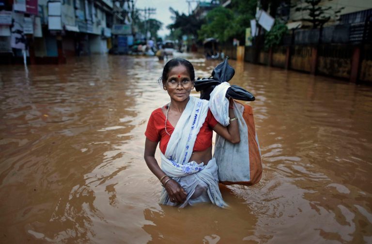 An Indian woman wades through the flood waters in Gauhati, India, Friday, June 27, 2014. Several people were killed due to electrocution and landslides triggered by incessant rains in Indiaâs northeastern state of Assam, according to local reports. (AP Photo/Anupam Nath)