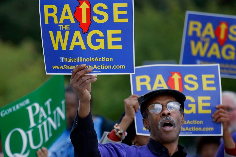 In this Thursday, Oct. 9, 2014 photo, supporters of raising the minimum wage rally outside where Democrat Illinois Gov. Pat Quinn and Illinois Republican gubernatorial candidate Bruce Rauner have their first televised debate in Peoria Ill. When Illinois voters cast ballots this year, they won't just get a chance to weigh in on a nationally watched governor's race. They also will have to wade through a record five ballot questions ranging from proposed constitutional amendments on voter rights and victim rights to poll-style referendum questions on birth control, a minimum wage hike and a proposed new tax on millionaires. (AP Photo/Seth Perlman)