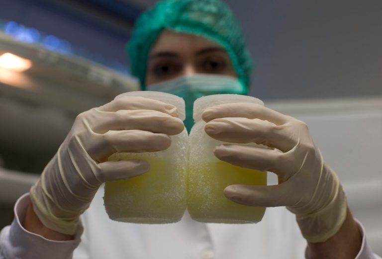 In this Aug. 27, 2014 photo, a lab technician shows a couple of containers of frozen donated human milk at the Fernandes Figueira Institute in Rio de Janeiro, Brazil. A group of American doctors are in Brazil to learn how the country's extensive milk bank system works. With more than 200 such banks nationwide, where breast-feeding women can donate milk that is then pasteurized and used in neo-natal facilities, Brazil has cut down dramatically in infant mortality. Doctors in the U.S. are looking to duplicate Brazil's success. (AP Photo/Silvia Izquierdo)