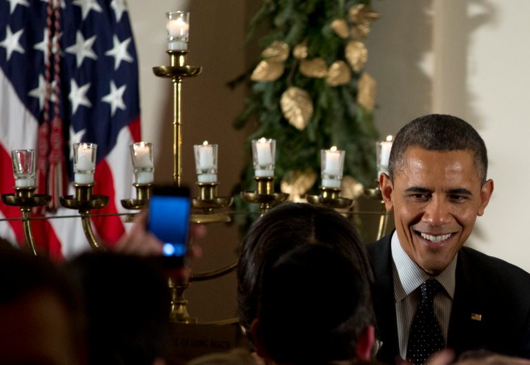   President Barack Obama greets people as he stands next to a lit Menorah during the Hanukkah reception in the Grand Foyer of the White House, Thursday, Dec. 13, 2012, in Washington. (AP Photo/Carolyn Kaster)  