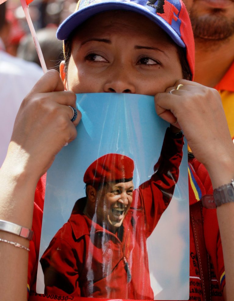 A woman holds a picture of Venezuela's President Hugo Chavez during an event commemorating the violent street protests of 1989 known as the 