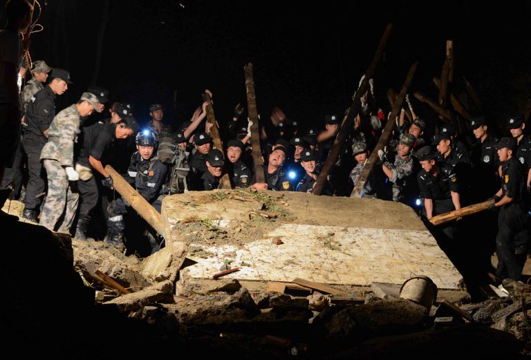Rescue workers lift a wall that collapsed after a landslide hit Yingping village in Fuquan city in southwest China's Guizhou province Thursday Aug. 28, 2014.   Six people died and 21 remained missing Thursday after a landslide hit a village in southwestern China, according to Chinese state media. (AP Photo) CHINA OUT