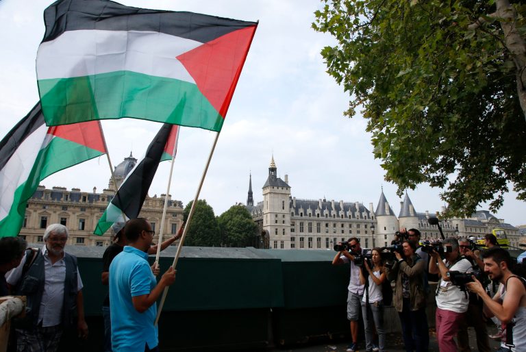 Protesters wave Palestinian flags from a bridge over the Seine River, during Paris Tel Aviv Beach event, in Paris, France, Thursday, Aug. 13, 2015. (AP Photo/Francois Mori)