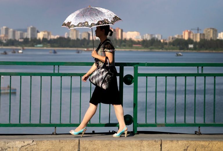 In this Aug. 30, 2014 photo, a North Korean woman walks along the Taedong River in Pyongyang, North Korea.  Most North Koreans remain too poor to think much about fashion, and the country in general maintains a deep-rooted resistance to outside influences. But in Pyongyang, where the standard of living is relatively high, clothes and styles have been changing in recent years - slowly and in a limited way, but more than many outsiders might think.(AP Photo/Wong Maye-E)