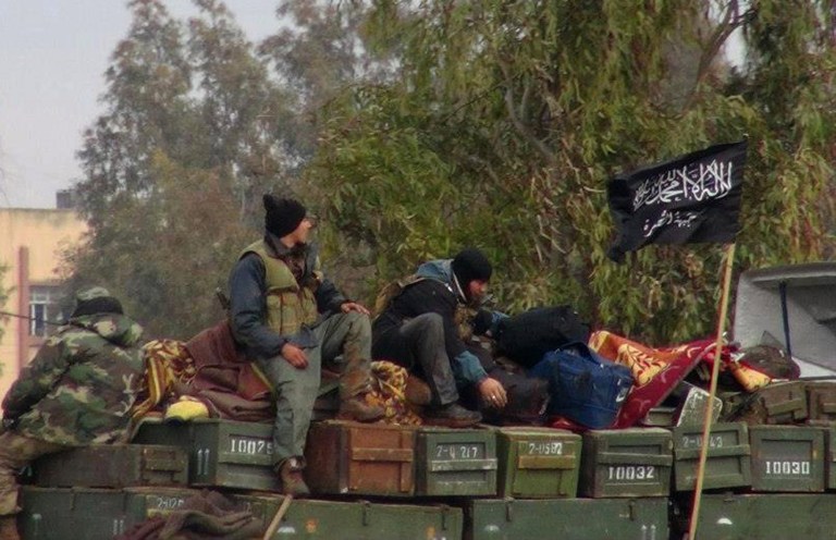FILE - In this Friday, Jan. 11, 2013 file citizen journalism image provided by Edlib News Network, ENN, which has been authenticated based on its contents and other AP reporting, shows rebels from al-Qaida affiliated Jabhat al-Nusra, as they sit on a truck full of ammunition, at Taftanaz air base, that was captured by the rebels, in Idlib province, northern Syria. Al-Qaida's branch in Iraq said it has merged with Syria's extremist Jabhat al-Nusra, a move that shows the rising confidence of radicals within the Syrian rebel movement and is likely to trigger renewed fears among its international backers. Arabic on the flag, right, reads, 