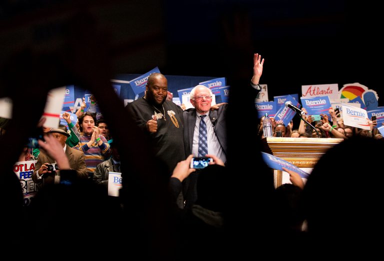 Democratic presidential candidate Sen. Bernie Sanders, I-Vt., right, waves to the crowd while standing with rapper Killer Mike at a campaign event at the Fox Theatre in Atlanta. (AP Photo/David Goldman)