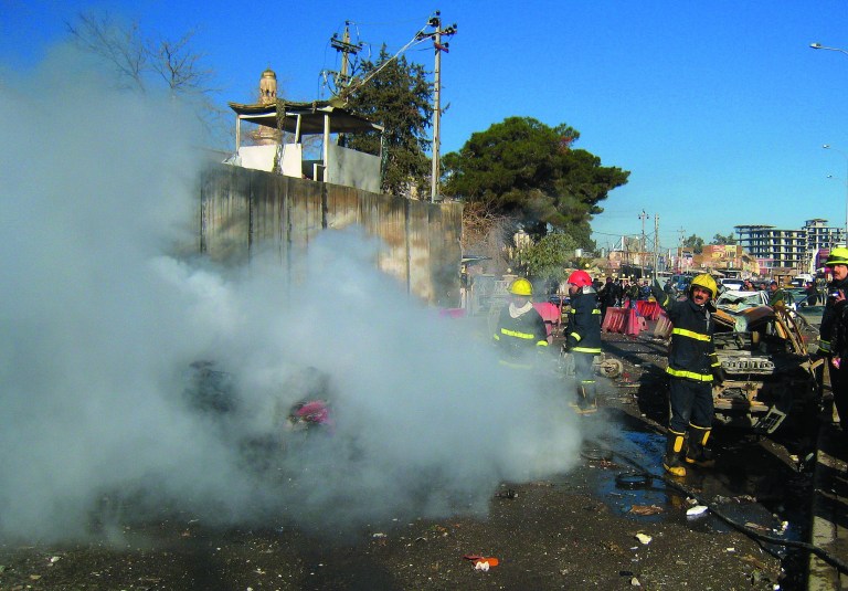 Iraqi firefighters distinguish a fire at the scene of a bomb attack in Kirkuk, 180 miles (290 kilometers) north of Baghdad, Iraq, Sunday, Feb. 3, 2013. A suicide car bomber joined by other suicide attackers on foot assaulted a provincial police headquarters in a disputed northern Iraqi city killing and wounding scores of people, police said. (AP Photo/Emad Matti)