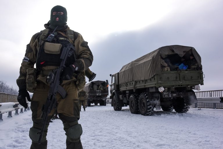 A pro-Russian rebel guards the road near the airport of Donetsk, with Ukrainian military vehicles at rear, Eastern Ukraine, Tuesday, Jan. 6, 2015. (AP Photo/Mstyslav Chernov)