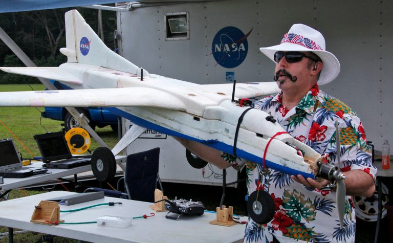 In this Friday Sept. 19. 2014 photo provided by NASA Langley Research Center, Mike Logan, a UAV engineer at NASA Langley, carries a UAV drone to the grassy airstrip of the Aviation History Museum in Pungo, Va. NASA is partnering with the U.S. Fish and Wildlife Service to test the use of drones to spot wildfires in the Great Dismal Swamp in southeastern Virginia and northeast North Carolina. (AP Photo/NASA Langley Research Center, David C. Bowman)