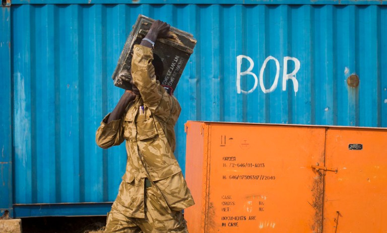 A South Sudanese government soldier carries an ammunition box from storage at the airport in Bor, Jonglei State, South Sudan Sunday, Jan. 19, 2014. Leaders for warring sides in South Sudan's monthlong internal conflict say they are close to signing a cease-fire and the South Sudanese military spokesman said that army forces had retaken the key city of Bor Saturday, defeating 15,000 rebels. (AP Photo/Mackenzie Knowles-Coursin)
