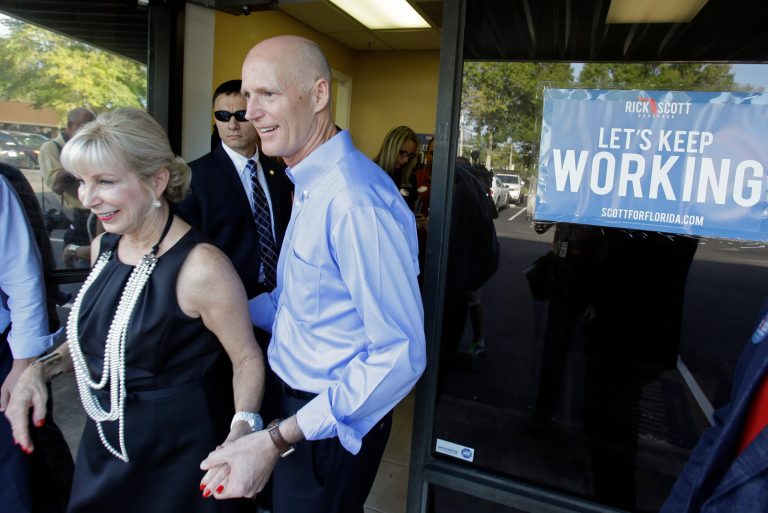 Florida Gov. Rick Scott, right, and his wife Ann, depart after a visit to a phone bank field office thanking volunteers for their work and support, Tuesday, Aug. 26, 2014, in Orlando, Fla.  Scott is seeking re-election for a second term as Florida's governor. (AP Photo/John Raoux)