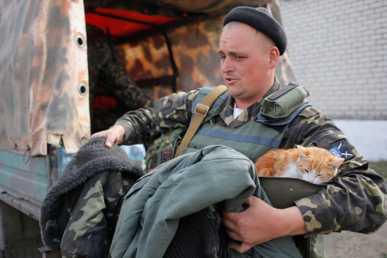 A Ukrainian soldier holds a cat as he receives warm clothes close to Luhansk in the eastern Ukraine Tuesday, Sept. 23, 2014.  Despite of the declared cease-fire between the separatists and the Ukrainian military in eastern Ukraine occasional shooting has been reported. (AP Photo/Petro Zadorozhnyy)