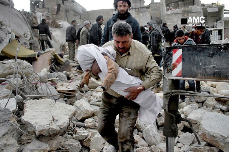 In this Wednesday, Jan. 29, 2014 citizen journalism image provided by Aleppo Media Center (AMC), an anti-Bashar Assad activist group, which has been authenticated based on its contents and other AP reporting, shows a Syrian man carrying the body of a child who was killed following a Syrian government airstrike in Aleppo, Syria. (AP Photo/Aleppo Media Center, AMC)