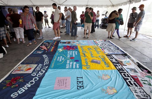 People gather around a section of the AIDS Memorial Quilt, on the National Mall in Washington, Saturday, July 21, 2012. The full quilt's display on the Mall was delayed due to rain. (AP Photo/Jacquelyn Martin)