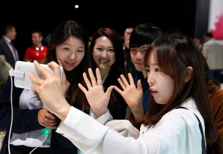 People pose for a selfie using LG's newly unveiled smartphone called the G3 at a press event in London, Tuesday, May 27, 2014. (AP Photo/Lefteris Pitarakis)