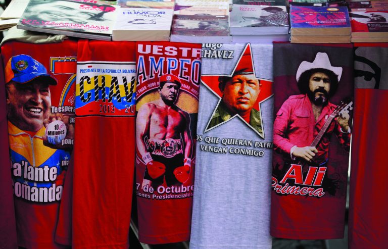 Iconic T-shirts styled with images of Venezuela's President Hugo Chavez are displayed for sale next to a T-shirt of Venezuelan musician Ali Primera, in Caracas, Venezuela, Friday, Dec. 28, 2012. The obsessive, circular conversations about Chavez's health dominate family dinners, plaza chit-chats and social media sites in this country on edge since its larger-than-life leader went to Cuba for emergency cancer surgery more than two weeks ago. The man whose booming voice once dominated the airwaves for hours at a time has not been seen or heard from since.(AP Photo/Fernando Llano)