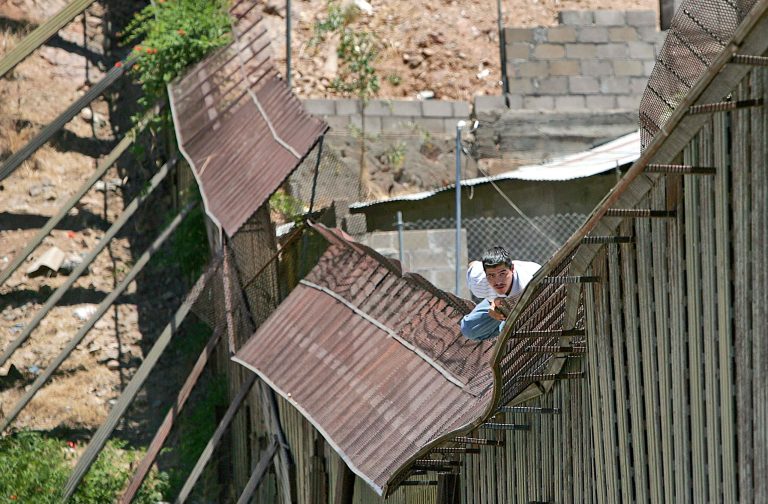 A man climbs over the international border into Nogales, Ariz., from Nogales, Mexico. A new suit charges that the federal government has overlooked the impact to the environment of millions of legal and illegal immigrants crossing into the U.S. (AP Photo/Matt York)