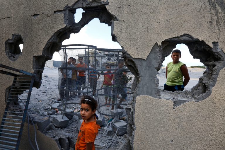 Palestinian Suma Abu Mahsen, 7, stands by a damaged wall of a house following an overnight Israeli missile strike to a nearby transition center for newly released convicts, that was not yet operational, in Rafah, southern Gaza Strip, Tuesday, July 15, 2014. An Egyptian truce proposal for the conflict in Gaza quickly unraveled Tuesday, after the Islamic militant group Hamas rejected the plan. (AP Photo/Lefteris Pitarakis)