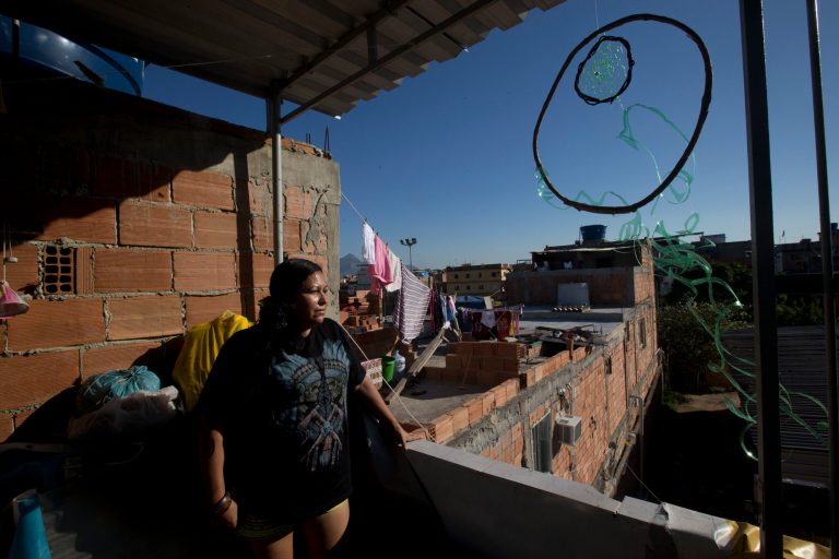 In this Aug. 24, 2014 photo, Vieira a Guarani indian gets a view of the Mare slum, next to a dream catcher hanging from the roof, in Rio de Janeiro, Brazil. Some 5,000 indians from across Brazil live in Rio's favelas, where many of them fight to keep their traditions alive amidst grinding poverty and rampant violence. (AP Photo/Silvia Izquierdo)