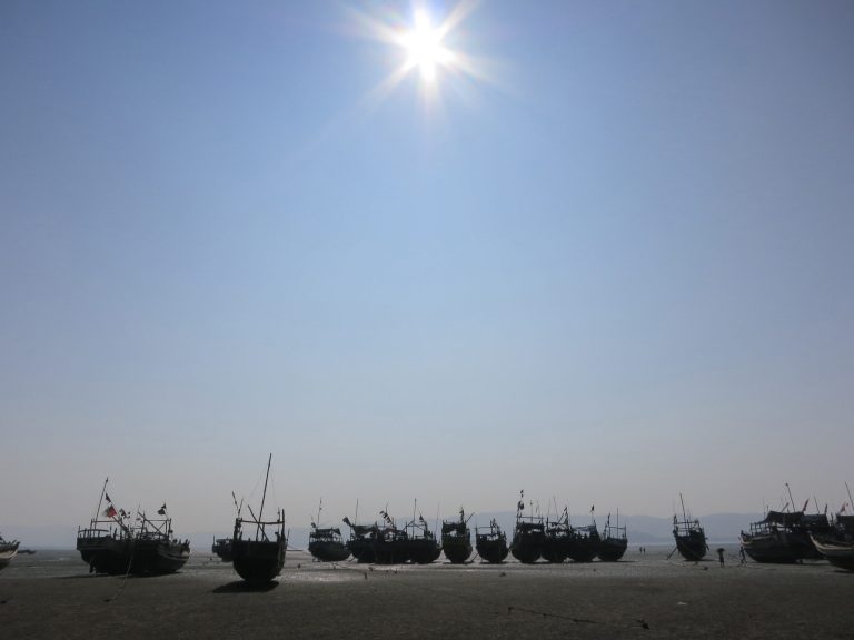   In this Sunday, Nov. 11, 2012 photo, a flotilla of wooden fishing boats belonging to Muslim refugees who fled the Myanmar port of Kyaukphu sit anchored during low tide on a beach in Sin Thet Maw, Myanmar. Stranded beside their decrepit flotilla of wooden boats, on a muddy beach far from home, the Muslim refugees tell story after terrifying story of their exodus from a once-peaceful town on Myanmar's western coast. (AP Photo/Todd Pitman)  