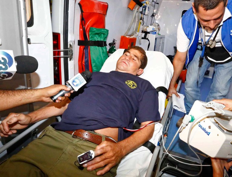 Jose Salvador Alvarenga, who lies on a stretcher in an ambulance is interviewed by reporters as he arrives at the hospital in Santa Tecla, El Salvador, Tuesday, Feb. 11, 2014. The 37-year-old, who says he survived more than a year on a small boat drifting from Mexico across the Pacific Ocean to the Marshall Islands, arrived in his native El Salvador late Tuesday. Alvarenga was reportedly arrived at the hospital for medical evaluation before returning to his home village of Garita Palmera. (AP Photo/La Prensa Grafica) EL SALVADOR OUT - NO PUBLICAR EN EL SALVADOR