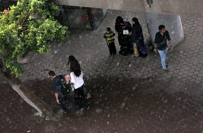 Egyptians take cover under a ramp as others walk on a street in the rain in Cairo, Egypt, Thursday, May 8, 2014. (AP Photo/Khalil Hamra)