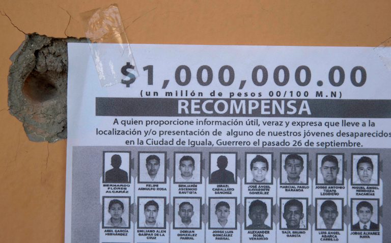 A poster offering a one million pesos for information on students who went missing hangs next to a bullet hole at the site where a small altar was erected by the spot where a student died recently in Iguala, Mexico, Tuesday, Oct. 7, 2014.  After the discovery of a mass grave and charges that local police may have conspired with a criminal gang to kill and disappear the students, President Enrique Pena Nieto ordered a special federal police force to take over the town as his top security officials rushed to contain a smear on the image of stability and falling crime rates that they've projected to the outside world. (AP Photo/Eduardo Verdugo)