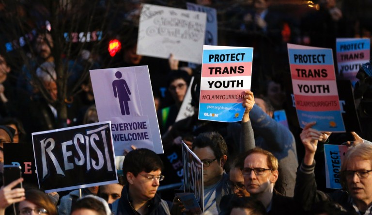 Protesters hold signs at a rally in support of transgender youth, Thursday, Feb. 23, 2017, at the Stonewall National Monument in New York. They were demonstrating against President Donald Trump's decision to roll back a federal rule saying public schools had to allow transgender students to use the bathrooms and locker rooms of their chosen gender identity.