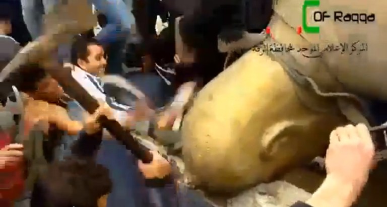 FILE - In this Monday, March 4, 2013 file image taken from video obtained from Ugarit News, which has been authenticated based on its contents and other AP reporting, Syrians attack a fallen statue of former Syrian President Hafez Assad in a central square in Raqqa, Syria. Since Raqqa fell under rebel control last week, opposition fighters have posted guards at government buildings to prevent looting, brought down the price of bread and opened a telephone hotline for residents to report security problems. Raqqa is shaping up as a test case for how rebels will administer their areas. (AP Photo/Ugarit News via AP video, File)