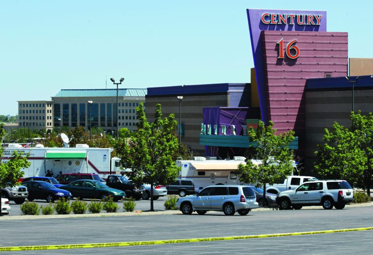 FILE - In this July 21, 2012 file photo, police and other vehicles remain in front of the Century 16 movie theater in Aurora, Colo. Relatives of the majority of people killed at the movie theater last July rejected an invitation on Wednesday, Jan. 2, 2013 to attend its reopening later this month, calling it a 