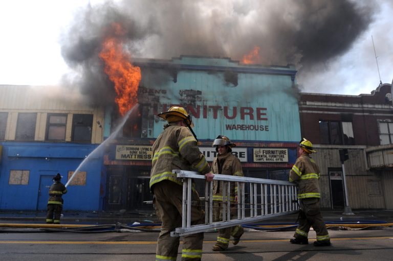 FILE - In this July 2, 2011, file photo firefighters carry a ladder at a fire in Detroit. A 41-page report filed Monday, May 13, 2013, by Detroit's emergency manager doesn't use the word 