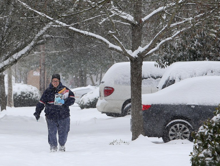 Postal employee Lisa Calloway trudges through the snow as she delivers mail in Eugene, Ore. on Friday, Feb. 7, 2014.  Snowfall starting late in the morning Friday will be widespread, dropping a foot or more in mountainous parts of Southern Oregon and 2 to 8 inches in Western Oregon valleys that got slammed Thursday, the National Weather Service said. (AP Photo/The Register-Guard, Brian Davies)