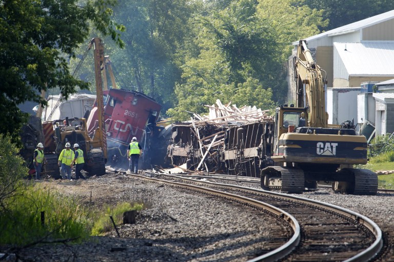 Workers clean up after a train derailment in Slinger, Wis., Monday, July 21, 2014. A southbound Canadian National train struck several Wisconsin & Southern Railroad cars around 8:30 p.m. Sunday at a rail crossing in Slinger, Wis., according to Patrick Waldron, a Canadian National spokesman. The derailment injured at least two people and spilled thousands of gallons of fuel that prompted the evacuation of dozens of homes, but evacuees were allowed to return around 1:30 a.m. Monday, Slinger Fire Chief Rick Hanke said. (AP Photo/Milwaukee Journal-Sentinel, Gary Porter)