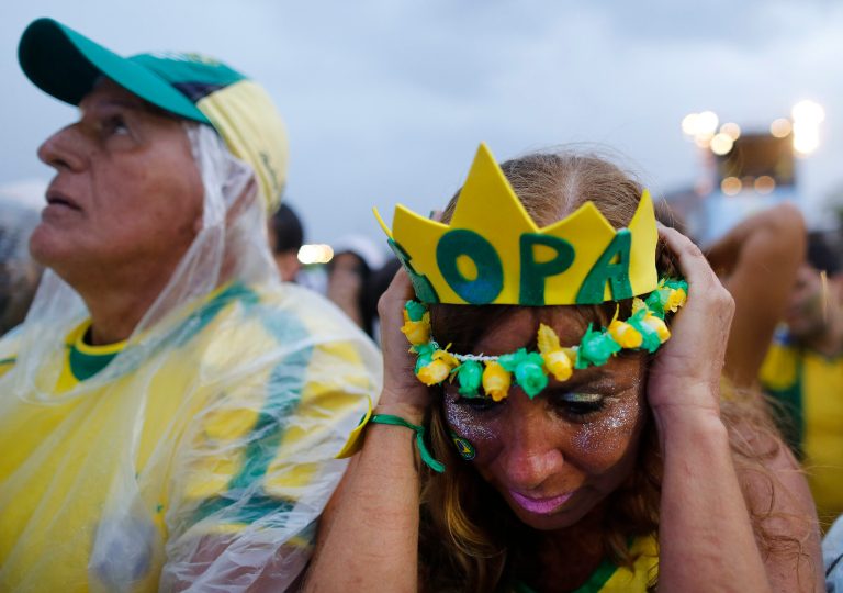 Brazil soccer fans wearing their team's colors Brazilian react as they watche their team play Germany in a World Cup semifinal game via live telecast inside the FIFA Fan Fest area on Copacabana beach in Rio de Janeiro, Brazil, Tuesday, July 8, 2014. Germany handed Brazil its heaviest World Cup loss ever with an astounding 7-1 rout in the semifinals that stunned the host nation. (AP Photo/Leo Correa)