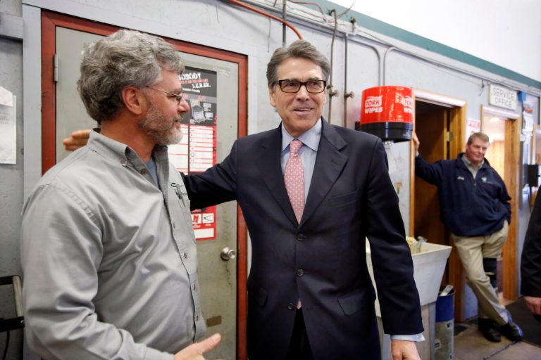 Former Republican Texas Gov. Rick Perry, right, talks with Weed Automotive owner Dan Weed Thursday, March 12, 2015, in Concord, N.H. (AP Photo/Jim Cole)